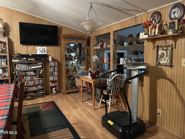 home office with wood walls, wood-type flooring, a textured ceiling, and ornamental molding