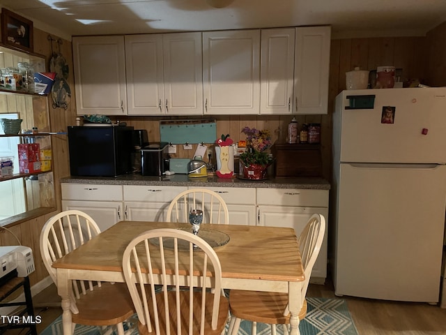 kitchen with white cabinets, white refrigerator, and hardwood / wood-style flooring