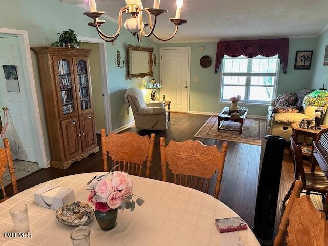 dining area with wood-type flooring, a notable chandelier, ornamental molding, and a textured ceiling