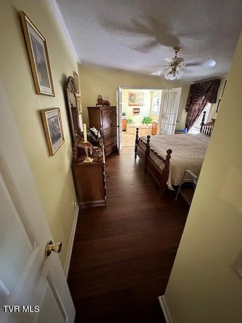 bedroom featuring dark wood-type flooring, a textured ceiling, and ceiling fan