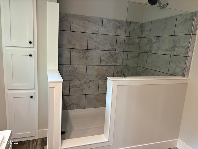 bathroom with a tile shower and wood-type flooring