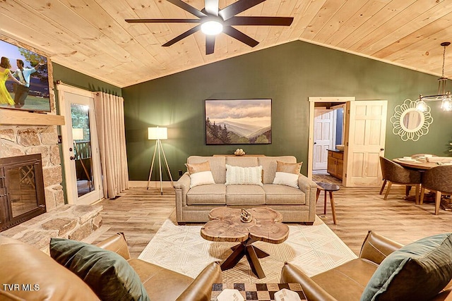 living room with vaulted ceiling, ceiling fan, light hardwood / wood-style flooring, wooden ceiling, and a stone fireplace