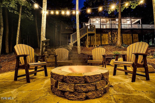 patio at twilight featuring a deck and an outdoor fire pit