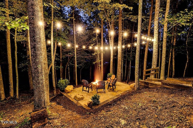 yard at night with a fire pit and a patio