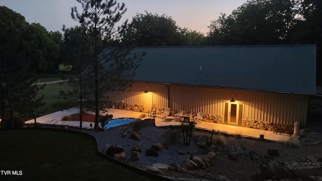2044 Pigeon Creek Rd, Greeneville, TN 37743 - back of house at dusk featuring stone siding, a patio area, and a swimming pool