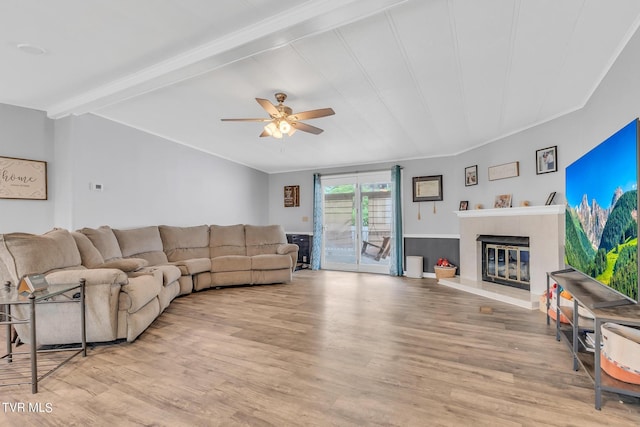 living area with a fireplace, ceiling fan, beamed ceiling, and wood finished floors