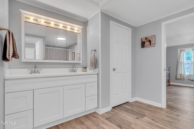 bathroom with crown molding, wood finished floors, baseboards, and a sink