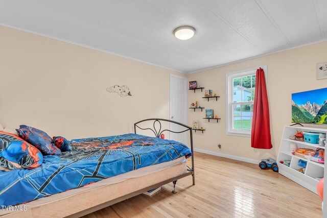 bedroom with baseboards, light wood finished floors, and crown molding