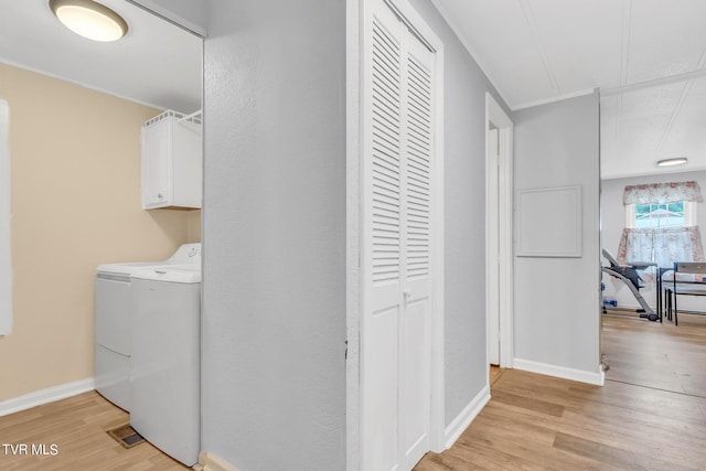 washroom with baseboards, separate washer and dryer, light wood-style flooring, and cabinet space