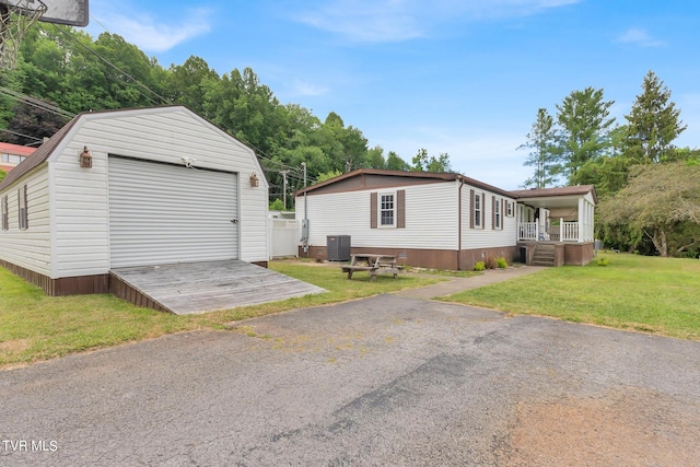 exterior space featuring an outdoor structure, a garage, central air condition unit, and a front yard