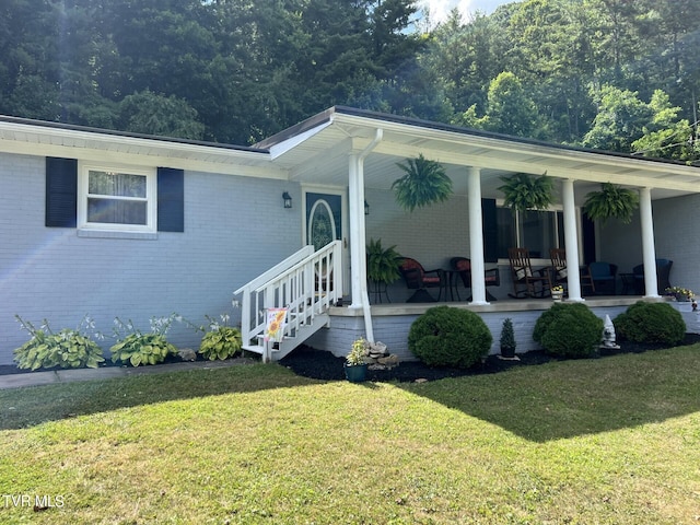 view of front of house featuring brick siding, a porch, and a front yard