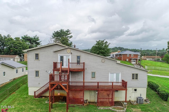 rear view of house featuring cooling unit, a wooden deck, a lawn, and french doors