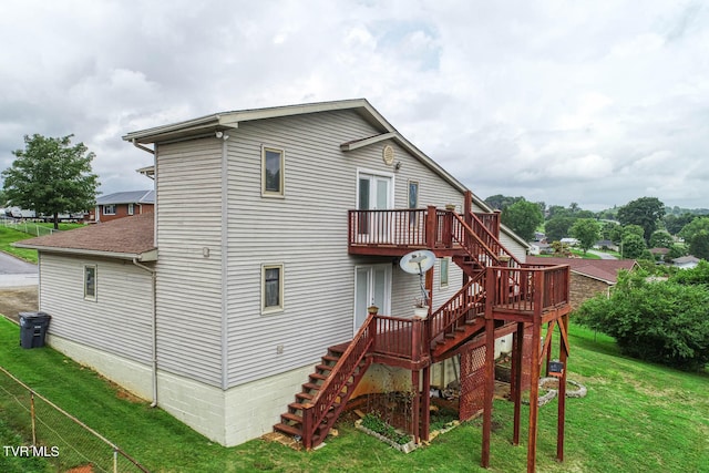 rear view of house featuring a wooden deck and a lawn