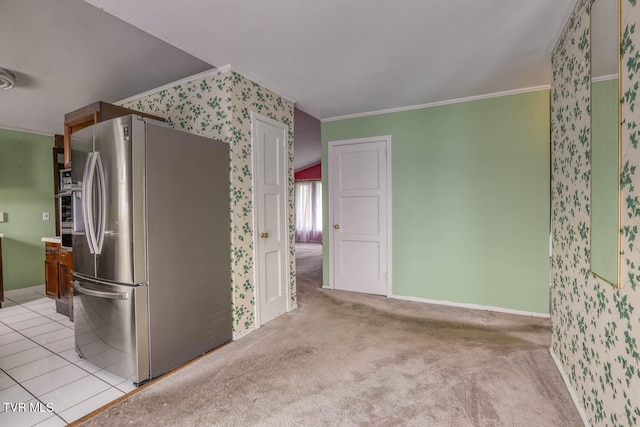 kitchen featuring stainless steel fridge, light tile patterned floors, and ornamental molding