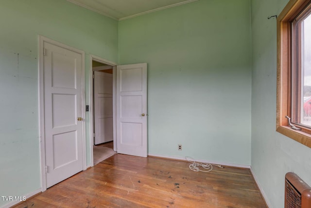 spare room with heating unit, hardwood / wood-style floors, ornamental molding, and a healthy amount of sunlight