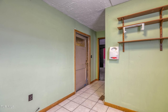 hallway with a textured ceiling and light tile patterned floors