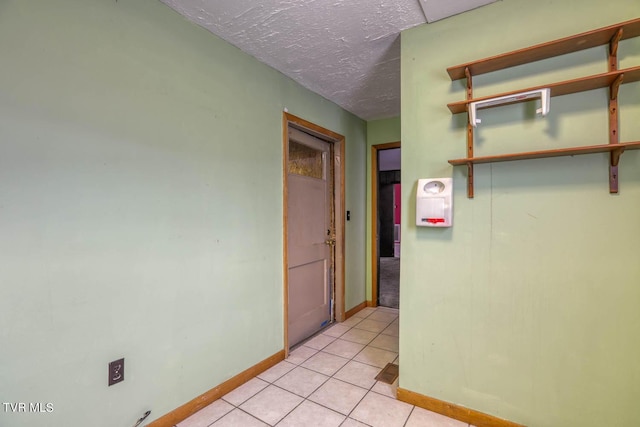 hall featuring light tile patterned floors and a textured ceiling