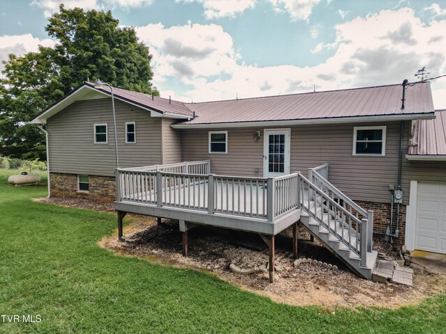 rear view of house featuring a yard, a garage, and a deck