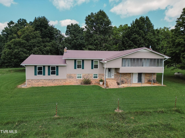 view of front of home featuring metal roof, a front lawn, a patio, and a sunroom