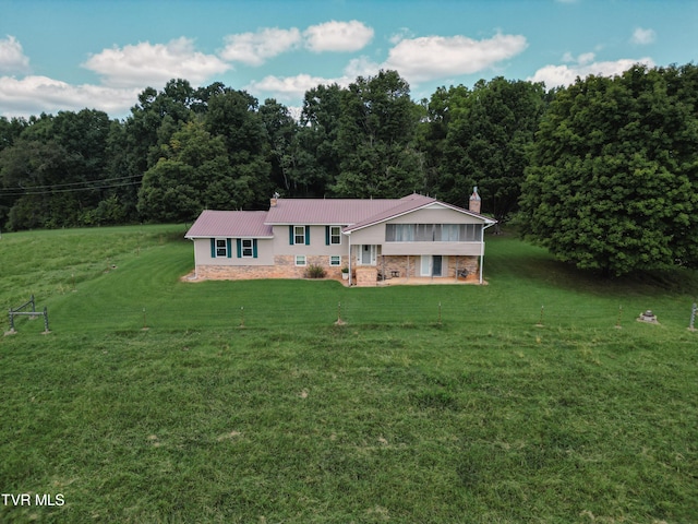 view of front of property with a chimney, metal roof, and a front yard