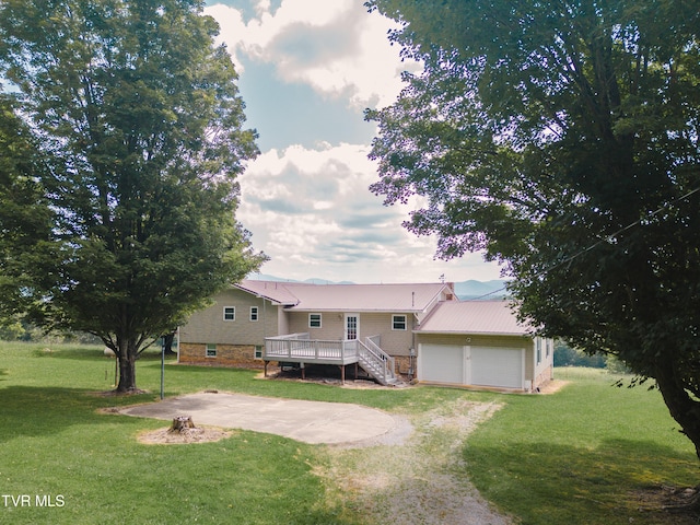 view of front facade featuring an attached garage, driveway, a wooden deck, a front lawn, and a patio area