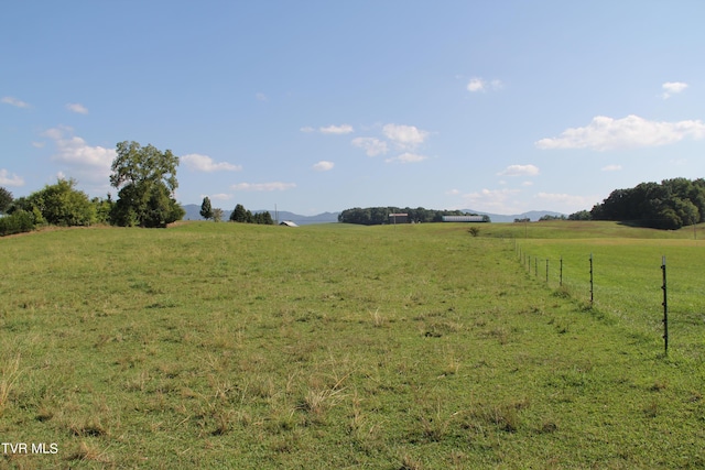 view of yard featuring fence, a mountain view, and a rural view