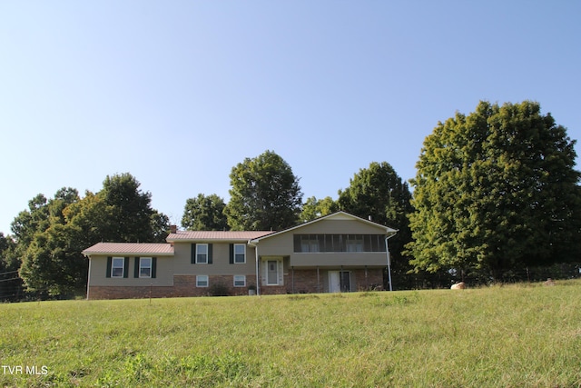 bi-level home featuring metal roof and brick siding