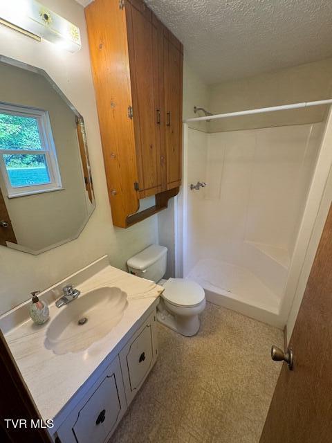 bathroom with a textured ceiling, a shower, toilet, and vanity