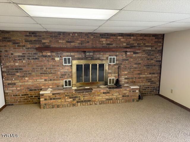 unfurnished living room with a fireplace, carpet flooring, and a drop ceiling