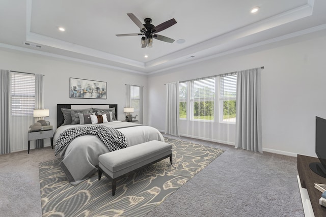 carpeted bedroom with ornamental molding, ceiling fan, and a raised ceiling