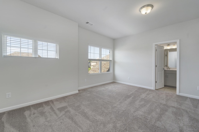 unfurnished bedroom with connected bathroom and light colored carpet