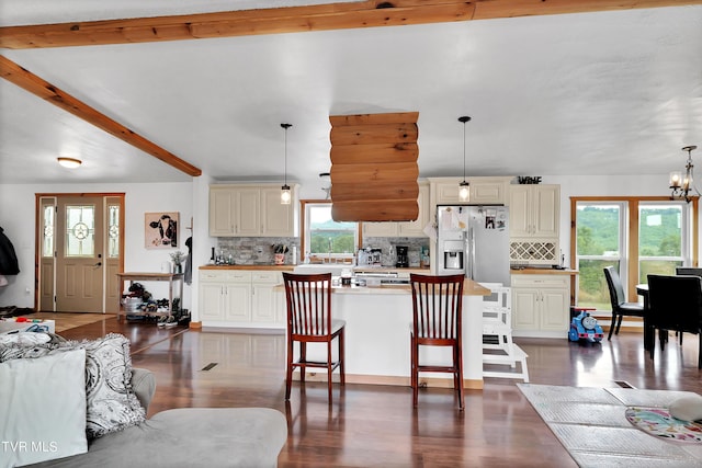 kitchen with pendant lighting, cream cabinets, a kitchen bar, and stainless steel fridge with ice dispenser