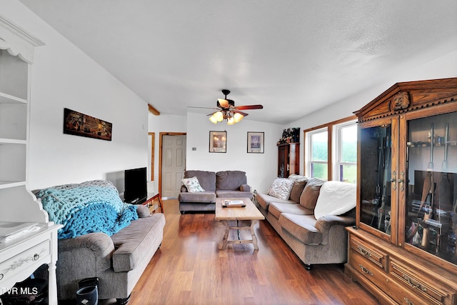 living room featuring lofted ceiling, a textured ceiling, hardwood / wood-style flooring, and ceiling fan