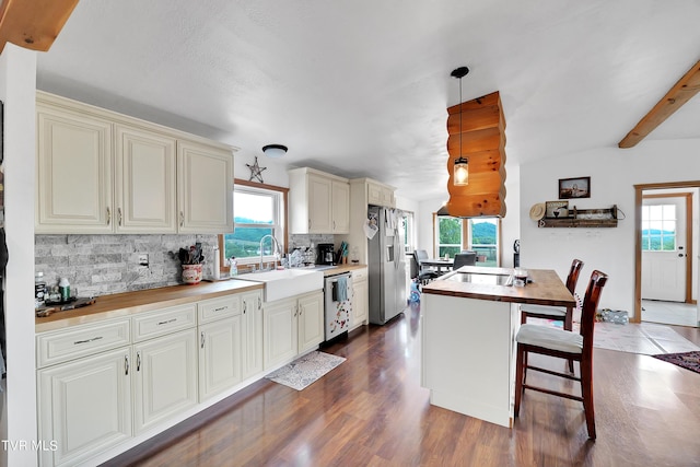 kitchen with butcher block countertops, sink, appliances with stainless steel finishes, hanging light fixtures, and cream cabinetry