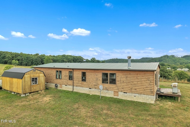 rear view of property with a yard, a deck, and a storage unit