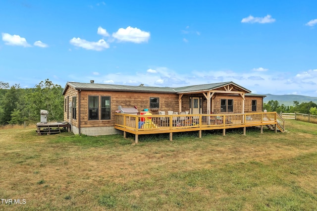 rear view of property with a deck with mountain view and a lawn