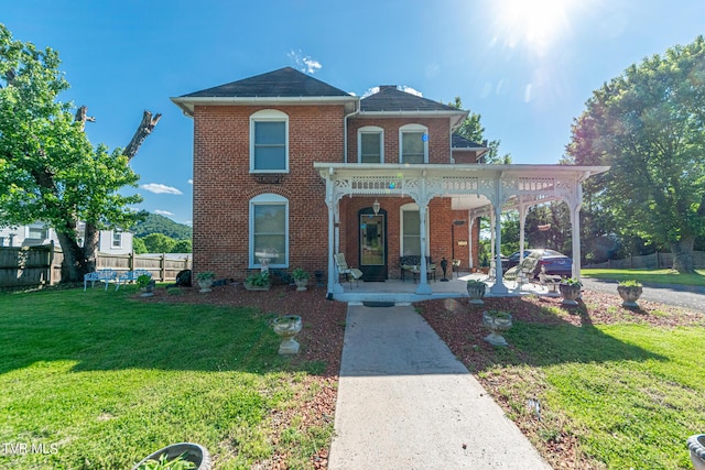 italianate house with a porch, fence, a front lawn, and brick siding