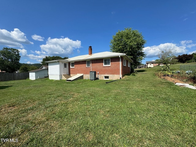 rear view of house with a lawn and a shed