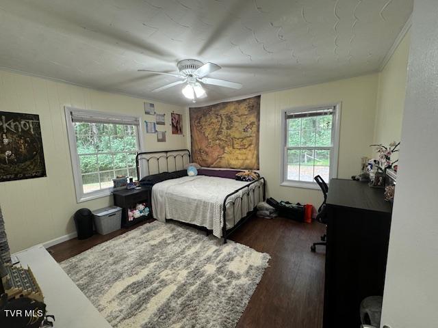 bedroom featuring dark wood-type flooring, crown molding, and ceiling fan