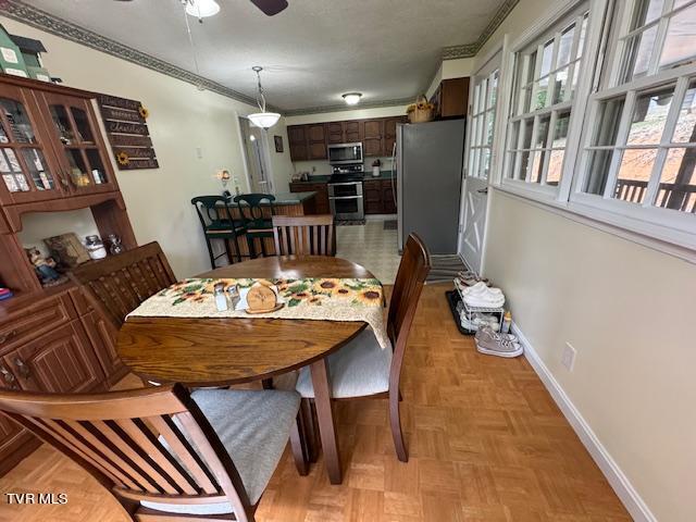 dining space with light parquet floors, ceiling fan, and crown molding