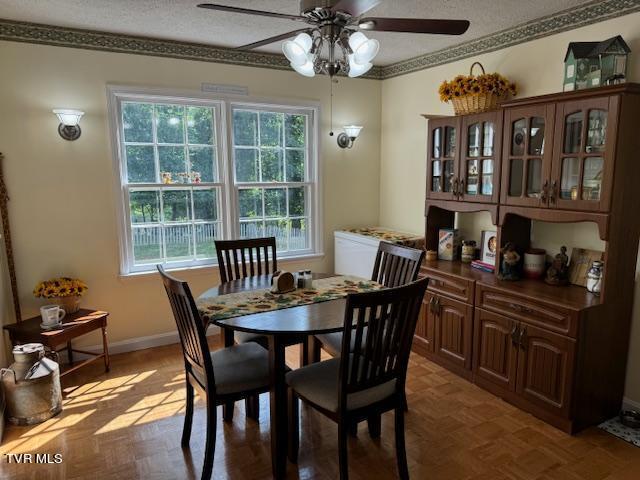 dining room featuring parquet floors, crown molding, a textured ceiling, and ceiling fan