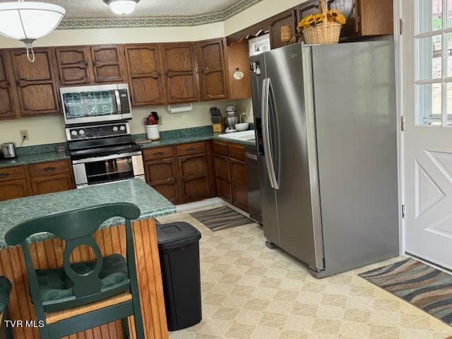 kitchen featuring light tile patterned flooring, appliances with stainless steel finishes, and decorative light fixtures