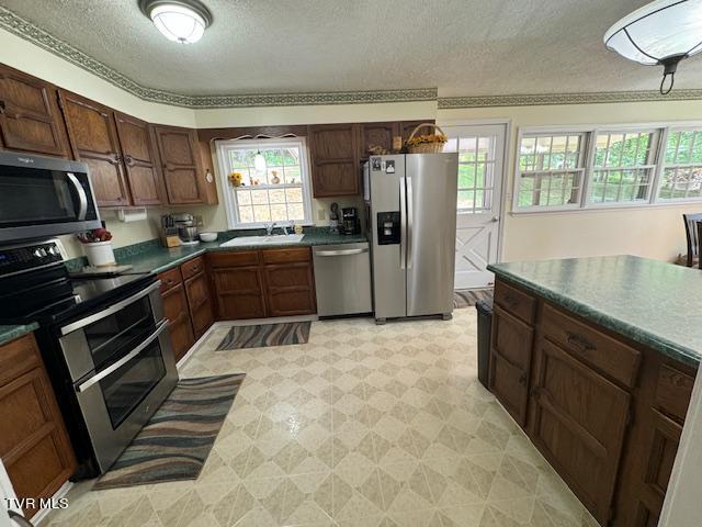 kitchen with appliances with stainless steel finishes, a textured ceiling, light tile patterned floors, and sink