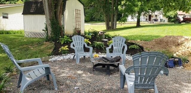 view of yard featuring an outdoor fire pit, an outbuilding, and a storage shed