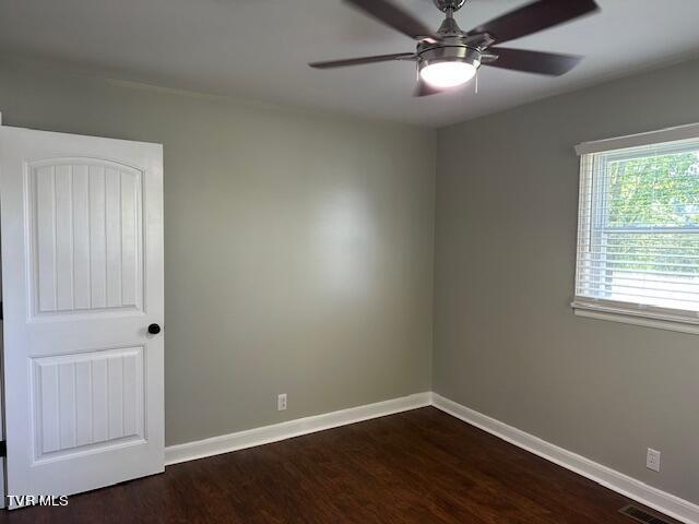 spare room featuring ceiling fan, baseboards, dark wood-style flooring, and visible vents