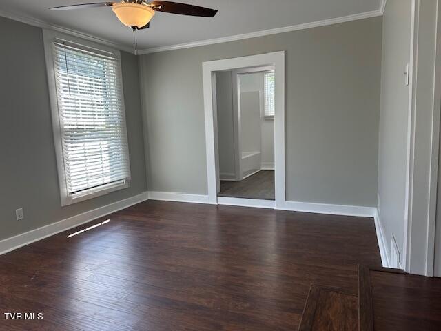 unfurnished bedroom featuring dark wood-type flooring, crown molding, baseboards, and multiple windows