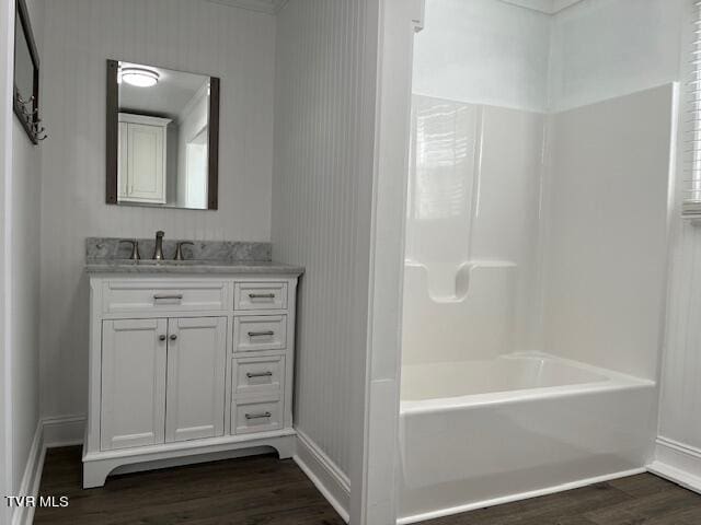 full bathroom with wood finished floors, vanity, baseboards, and bathing tub / shower combination