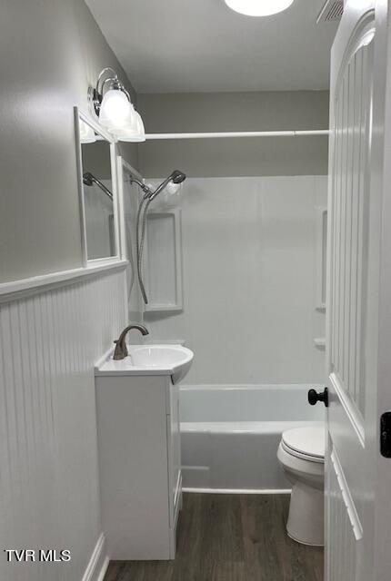 full bathroom with wood finished floors, vanity,  shower combination, toilet, and visible vents