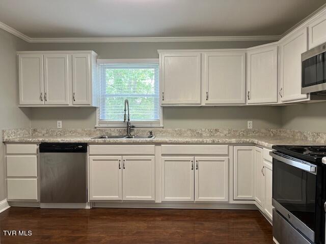 kitchen with white cabinets, appliances with stainless steel finishes, ornamental molding, and a sink