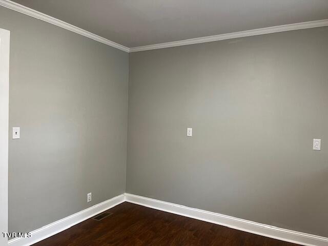 spare room featuring dark wood finished floors, baseboards, and ornamental molding